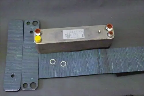 Brötje Wärmetauscher in rechteckiger Bauform mit mehreren Anschlüssen und Dichtungsringen, umgeben von isolierenden Materialien.