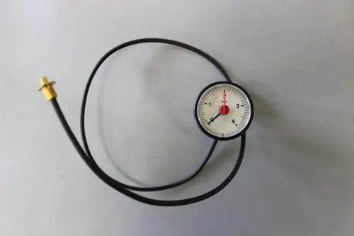 Manometer mit einem Ziffernblatt und einem schwarzen Schlauch, verbunden mit einem goldenen Anschluss. Produkt von Brötje zur Druckmessung.