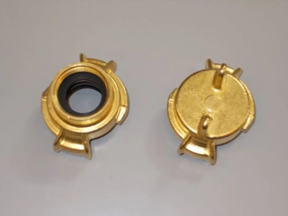 Brötje Kupplung in goldener Farbe, mit zwei Halteklammern an den Seiten. Eine Seite zeigt eine Gummieinlage, die andere eine flache, runde Oberseite.