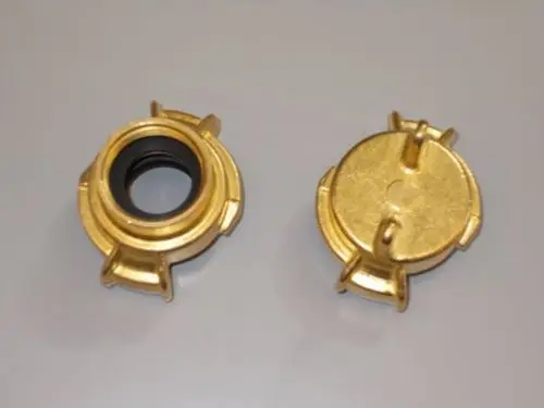 Brötje Kupplung in goldener Farbe, mit zwei Halteklammern an den Seiten. Eine Seite zeigt eine Gummieinlage, die andere eine flache, runde Oberseite.