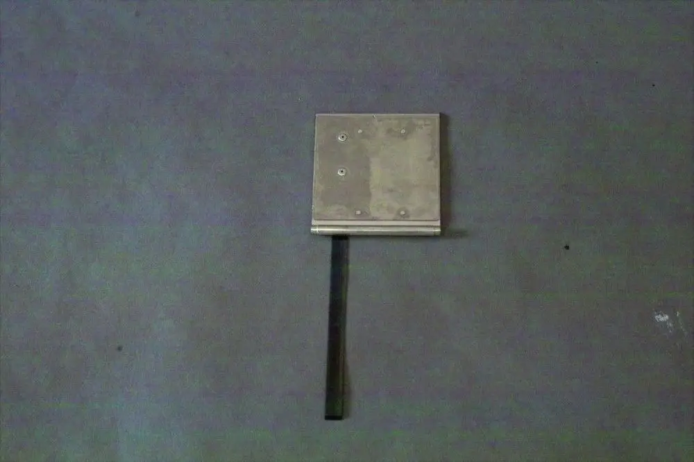 Brötje Luftklappe mit quadratischem Metallgehäuse und einem flachen, vertikalen Hebel, montiert auf einer grauen Oberfläche.