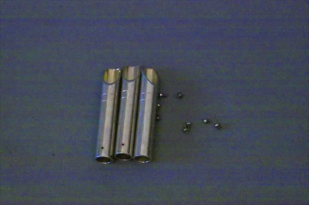 Brötje Produkt mit drei metallischen Rohren und mehreren kleinen Schrauben, auf einer neutralen Oberfläche angeordnet.