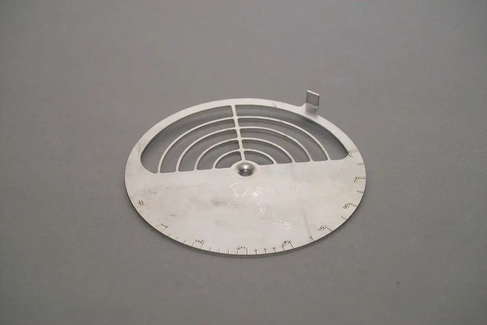Brötje Luftklappe aus Metall mit mehreren parallel verlaufenden Lamellen und einer mittigen Öffnung, die die Luftverteilung steuert, auf grauem Hintergrund.