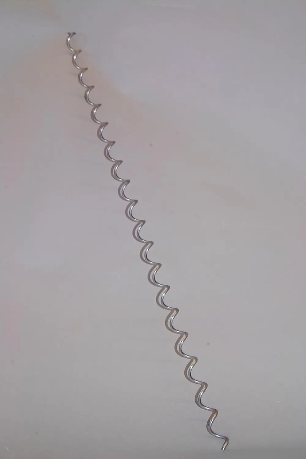 Brötje Wirbulator in Wellenform aus Metall, auf einer flachen Oberfläche platziert. Das Produkt hat eine klare, durchgehende Struktur ohne erkennbare Details zu Maßen oder spezifischen Merkmalen.