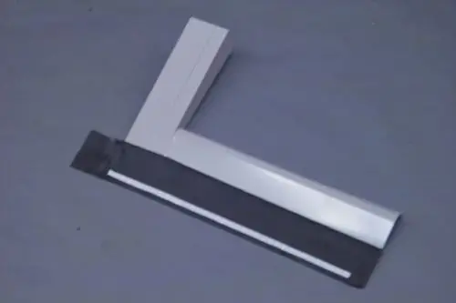 Rechteckige Metallplatte in heller Farbe mit einem L-förmigen Element, möglicherweise Teil eines Brötje Heizungszubehörs, auf grauem Untergrund.