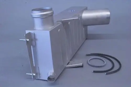 Brötje Gehäuse eines Plattenwärmetauschers aus Metall, mit einem Ansatzrohr und Befestigungsschrauben, liegt auf einer grauen Unterlage.