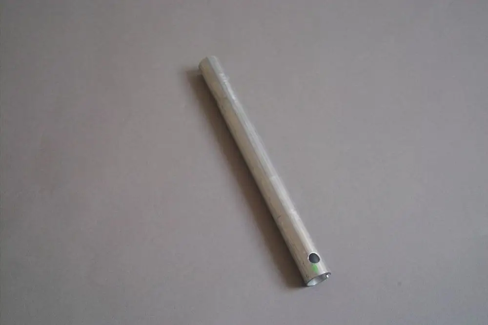 Metallrohr mit einer glatten Oberfläche und zwei Löchern an einem Ende. Es könnte Bestandteil einer Brötje-Heizungsanlage sein.
