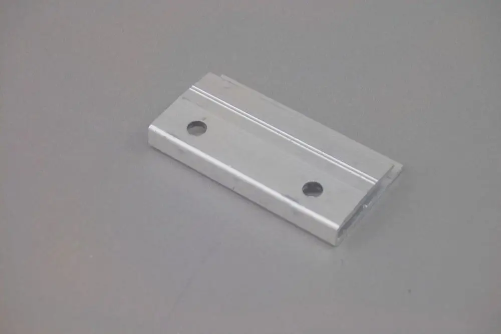 Aluminium-Klemmstück von Brötje, rechteckig mit zwei Löchern und einer gerundeten Kante, auf neutralem Hintergrund.