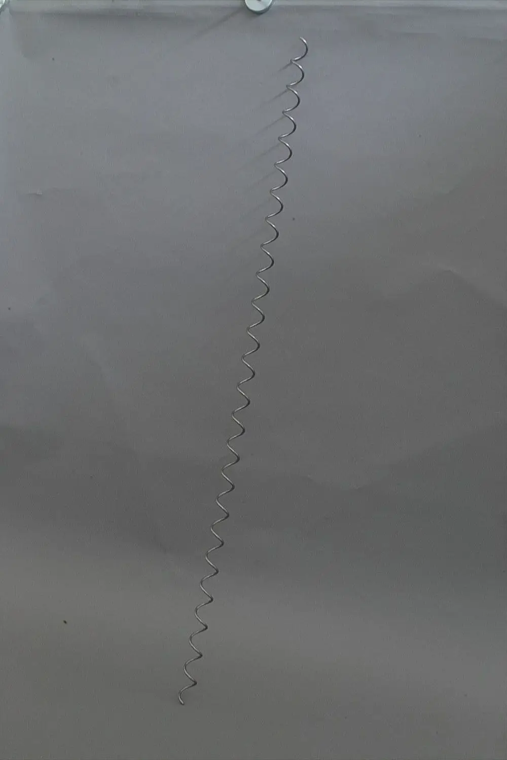 Schraubenförmiger Wirbulator aus Metall, montiert an einer Aufhängung, vor grauem Hintergrund. Produkt von Brötje.