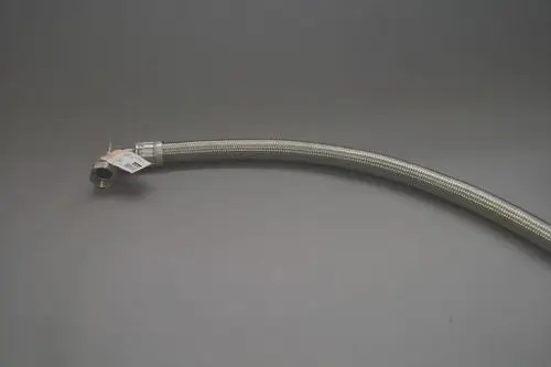 Flexibler Schlauch mit Metallummantelung und einer Verbindungsmutter, gekennzeichnet für Brötje Produkte. Überwiegend schräg liegend auf grauem Hintergrund.