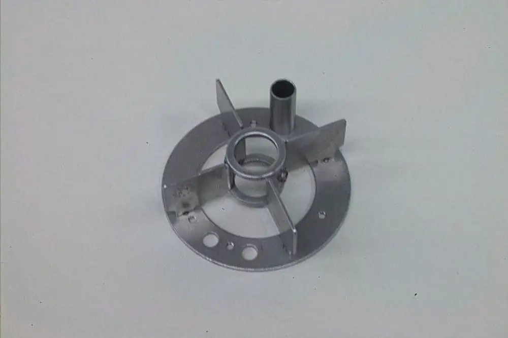 Metallischer Zentrierring mit gewölbter Form, mehreren Löchern und vertikaler Rohröffnung, geeignet für Anwendungen im Bereich Heizung, möglicherweise von Brötje.