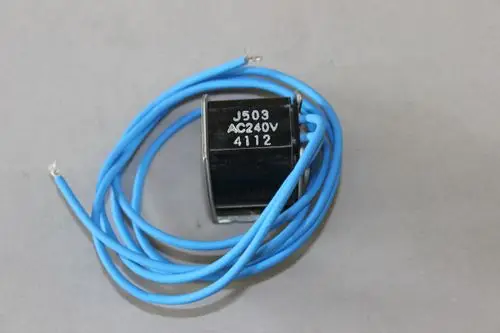 Schwarze Brötje-Spule mit blauen Drähten, beschriftet mit "J503 AC240V 4112", auf grauem Hintergrund. Die Spule hat eine kompakte Bauform.