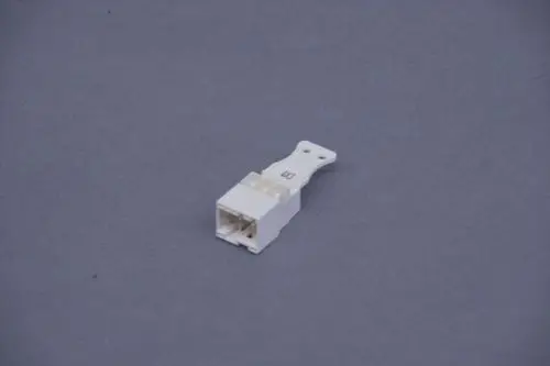 Weißer Kunststoffstecker von Brötje mit mehreren Kontaktstiften und einem Halteclip, auf grauem Hintergrund.