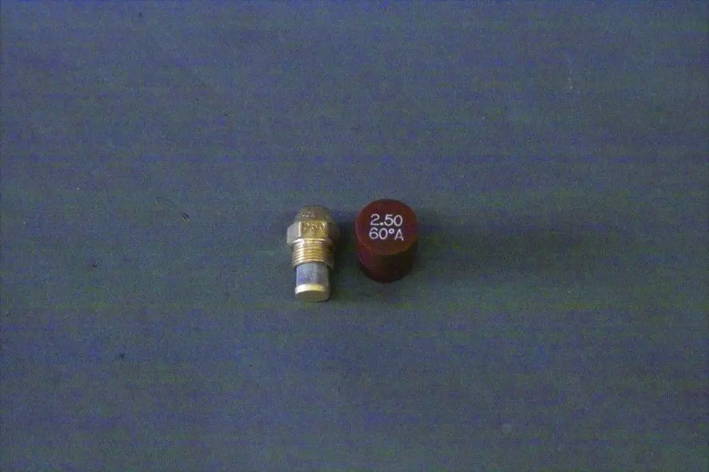 Brötje Düse mit einem goldenen Kopf und rotem Zylinder, die eine Beschriftung aufweist. Die Düse liegt auf einer grauen Oberfläche.