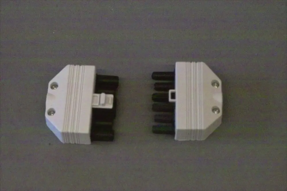 Zwei weiße Brötje Buchsen/Stecker mit jeweils sechs schwarzen Pins, auf grauem Hintergrund angeordnet.