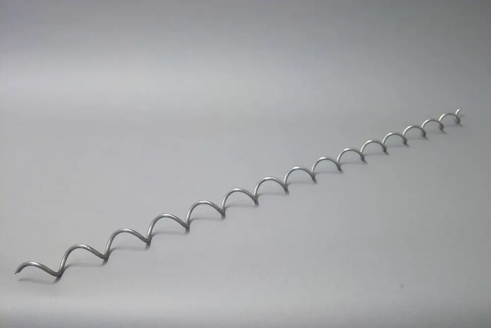 Brötje Wirbulator, metallische Spirale mit gleichmäßigen Wellen, auf heller Oberfläche liegend. Klare Struktur, keine sichtbaren Maße.