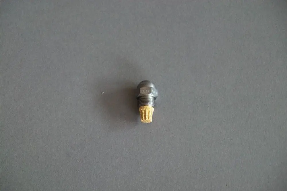 Brötje Düse mit runder, metallischer Form, einer goldfarbenen Unterseite und mehreren kleinen Öffnungen, auf grauem Hintergrund abgebildet.