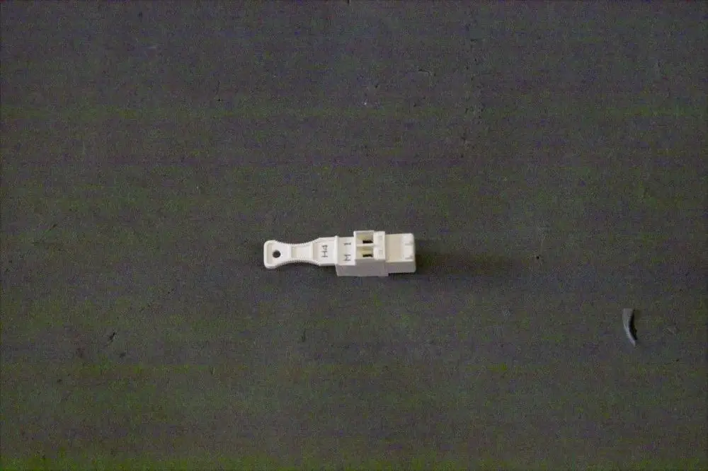 Weißer Stecker von Brötje auf grauem Untergrund, mit mehreren Anschlüssen, erkennbar sind die Bezeichnungen "H" und "M".