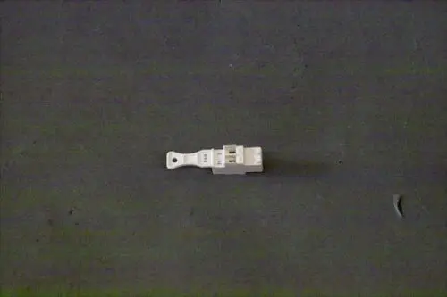 Weißer Stecker von Brötje auf grauem Untergrund, mit mehreren Anschlüssen, erkennbar sind die Bezeichnungen "H" und "M".