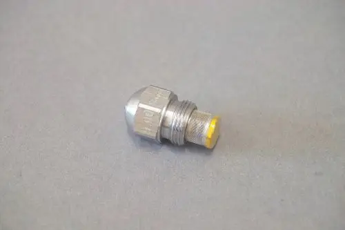 Brötje Düse aus Metall mit hexagonalem Kopf und Gewinde, geeignet für Heizungsanwendungen. Die Düse zeigt eine runde Öffnung an der Unterseite.