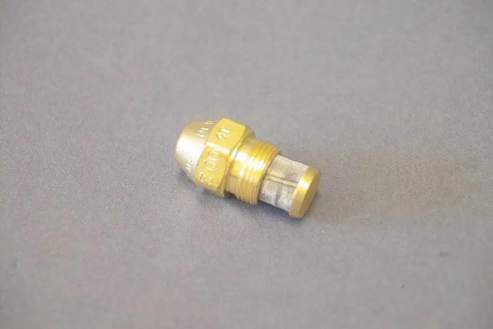 Brassdüse von Brötje mit konischer Form und einem Netzfilter, auf grauem Hintergrund liegend. Ideal für Anwendungen in Heizsystemen.