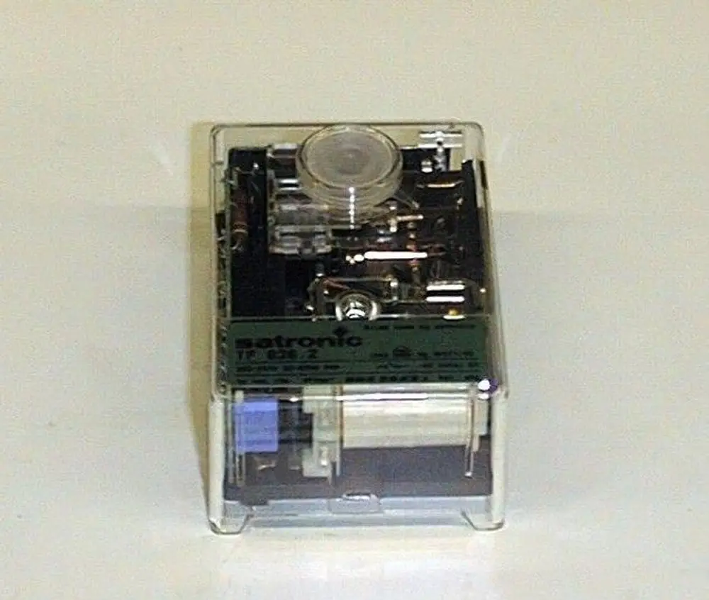 Brötje Ölfeuerungsautomat in transparenter Box, zeigt interne Mechanik und elektronische Komponenten. Verwendung in Heizsystemen zur Regelung von Ölfeuerungen.