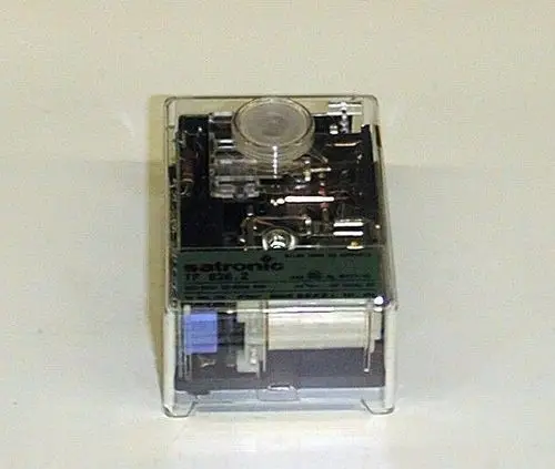 Brötje Ölfeuerungsautomat in transparenter Box, zeigt interne Mechanik und elektronische Komponenten. Verwendung in Heizsystemen zur Regelung von Ölfeuerungen.