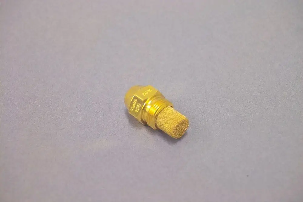 Goldfarbener, zylindrischer Düse von Brötje mit einem schaumstoffartigen Filter an der Spitze, auf einer grauen Unterlage platziert.