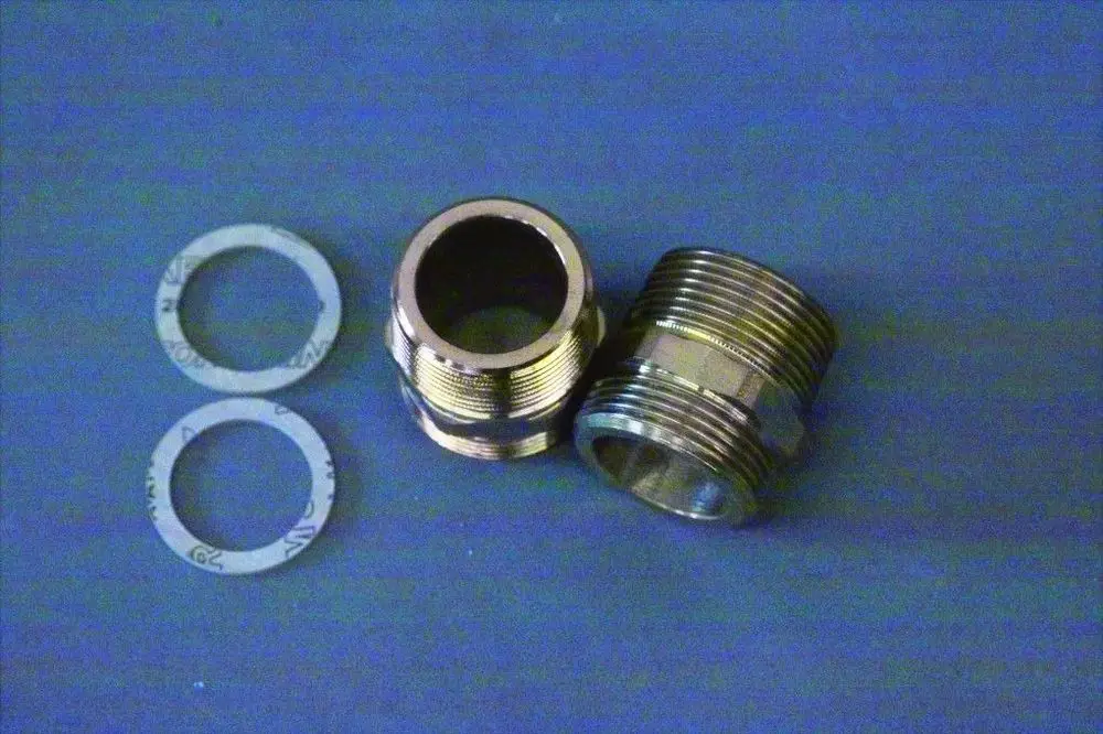 Brötje Doppelnippel aus Metall mit zwei gewindeten Enden. Daneben liegen zwei Dichtungen. Die Oberfläche der Nippel ist glatt und glänzend.
