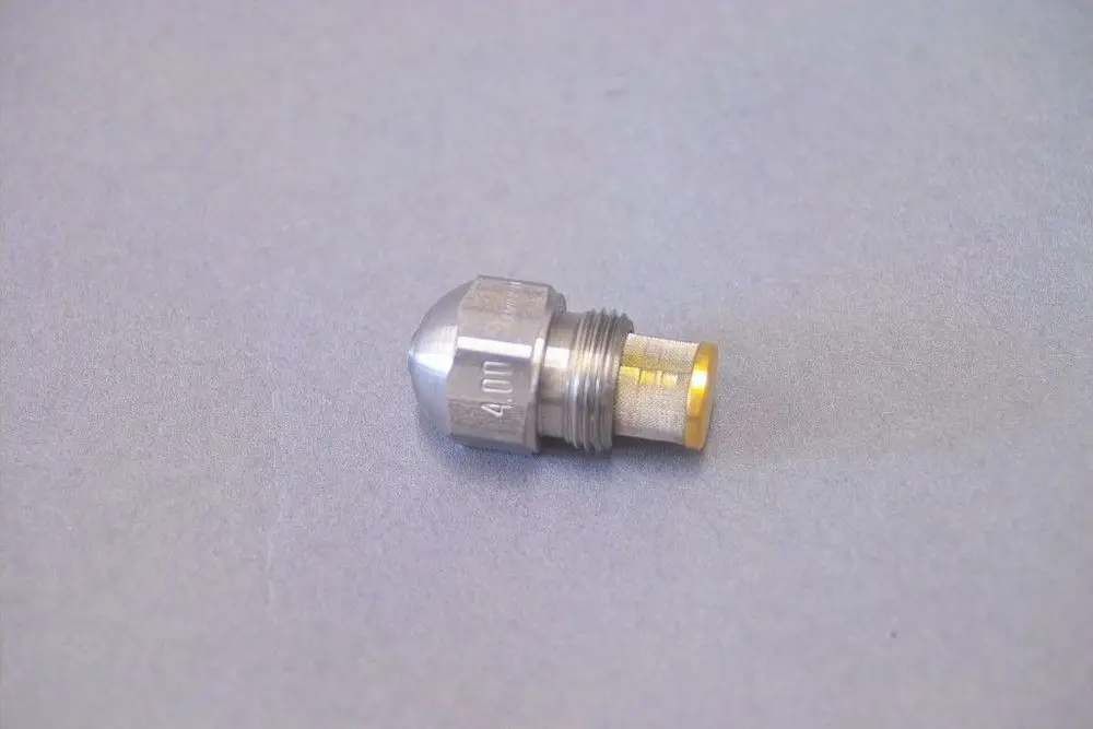 Brötje Düse aus Metall, mit konischer Spitze und einem Gewinde, liegend auf grauem Hintergrund.
