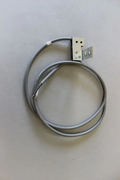 Brötje Schalter mit grauem Kabel und Metallhalterung auf grauem Untergrund. Zwei Kabelenden sind sichtbar, eines mit freiliegenden Drahtenden.