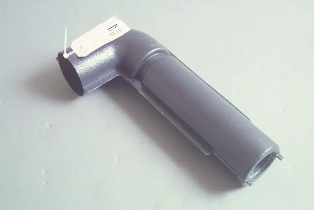 Grauer Ansaugschalldämpfer mit gebogenem Ende und einer offenen Seite, erkennbar als Produkt von Brötje, auf grauem Hintergrund.