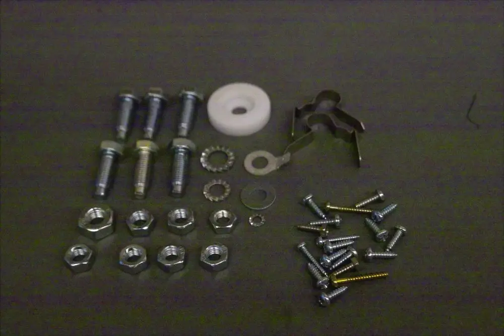 Schrauben und Unterlegscheiben von Brötje, angeordnet auf einer Fläche. Verschiedene Größen und Typen von Schrauben sind sichtbar, einschließlich spezifischer Metallteile.