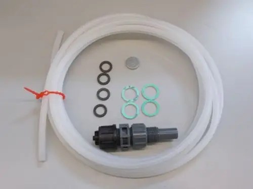 Brötje Wartungs-Set mit flexiblen Schläuchen, Dichtungsringen, einer Verbindung und einer Münze als Größenreferenz auf einem neutralen Hintergrund.