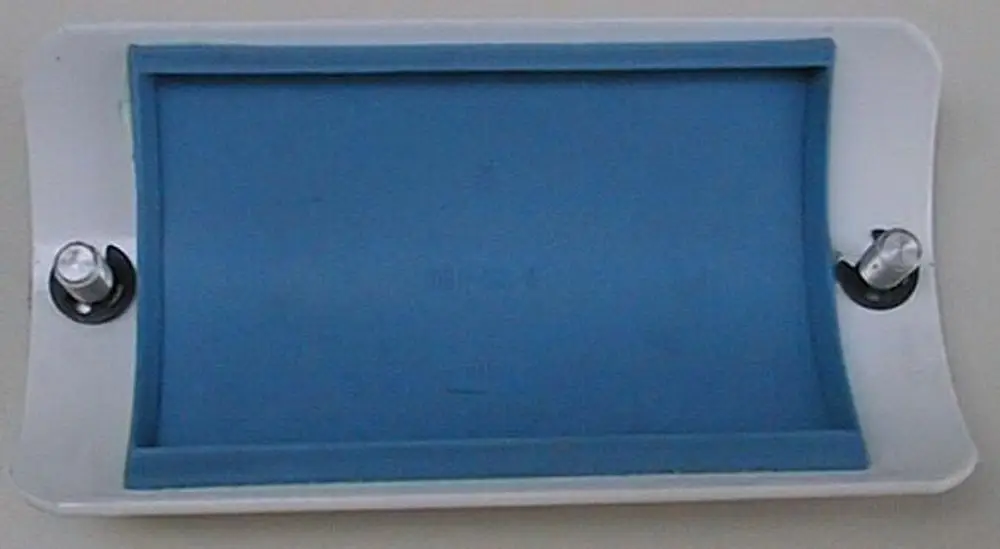 Reinigungstür mit blauer Gummidichtung und zwei Rändelschrauben, montiert auf einer weißen Oberfläche, zugehörig zu Brötje-Produkten für Heizsysteme.