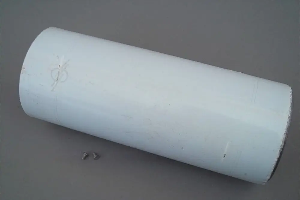 Weißes Rohr mit einer glatten Oberfläche, das auf einer Unterlage liegt. Daneben befinden sich zwei kleine Schrauben. Das Produkt könnte im Kontext von Brötje verwendet werden.