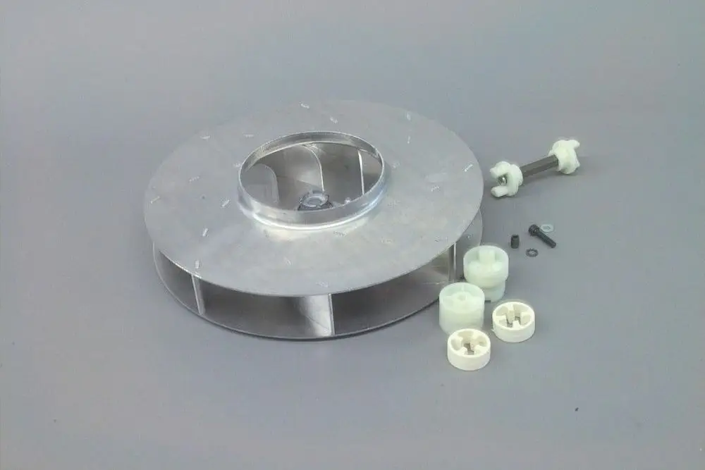 Brötje Gebläserad aus Aluminium mit mehreren Öffnungen, umgeben von verschiedenen Montageelementen, darunter Kunststoffteile und Schrauben.