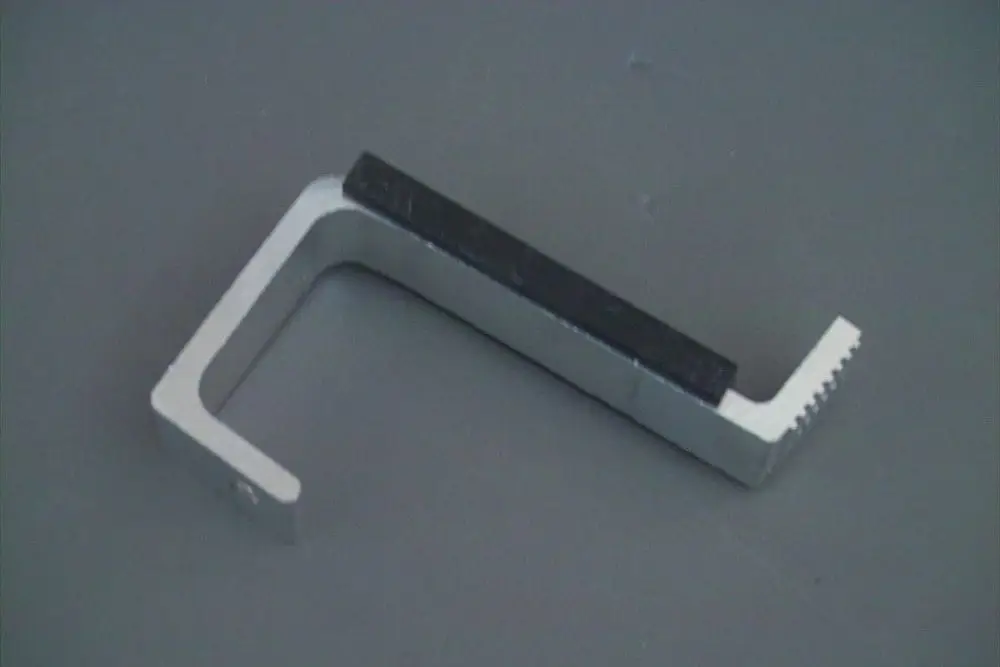 Brötje Halterung aus Aluminium mit schwarzem Griff und gezahnter Kante, geeignet zur Befestigung von Dachsystemen.