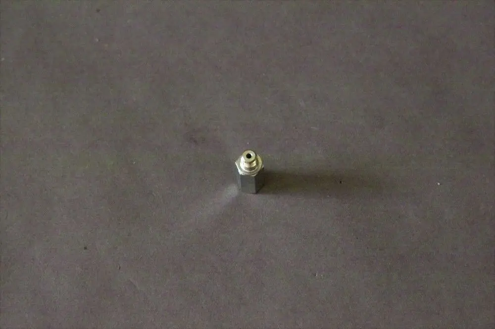 Brötje Nippel in metallischer Ausführung, mit einem Anschluss auf der Oberseite und einem zylindrischen Körper. Auf grauem Untergrund platziert.