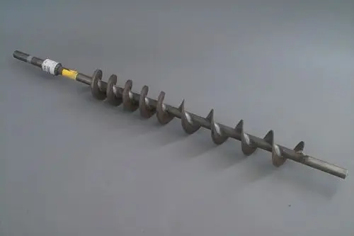 Brötje Förderspirale aus Metall mit mehreren Schraubenwindungen, die sich entlang eines geraden Schaftes erstrecken, auf grauem Hintergrund.