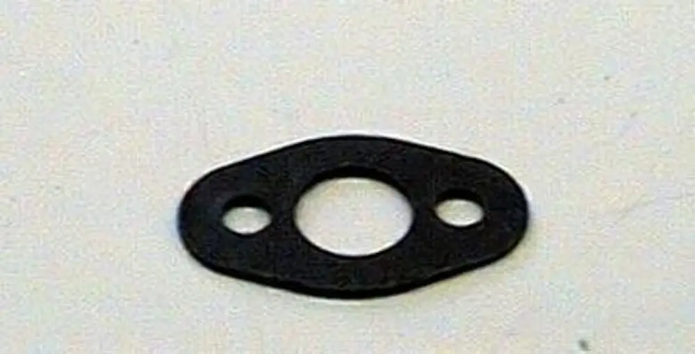 Schwarze Dichtung von Brötje, oval mit zwei seitlichen Bohrungen und einem mittigen Loch, auf heller Unterlage.