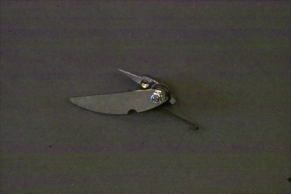 Brötje Luftklappenregelsystem, bestehend aus einem metallischen Teil mit beweglichen Klappen und einer Federmechanik, auf grauem Hintergrund abgebildet.