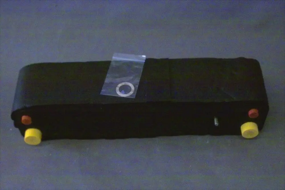 Schwarzer Wärmetauscher von Brötje mit gelben und roten Bedienelementen. Ein transparenter Beutel mit einem Ring liegt darauf.