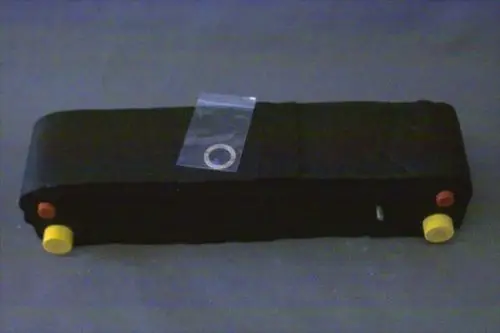 Schwarzer Wärmetauscher von Brötje mit gelben und roten Bedienelementen. Ein transparenter Beutel mit einem Ring liegt darauf.