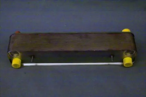 Brötje Wärmetauscher in rechteckiger Form, mit zwei farbigen Anschlüssen auf beiden Seiten, montiert auf einem grauen Untergrund.