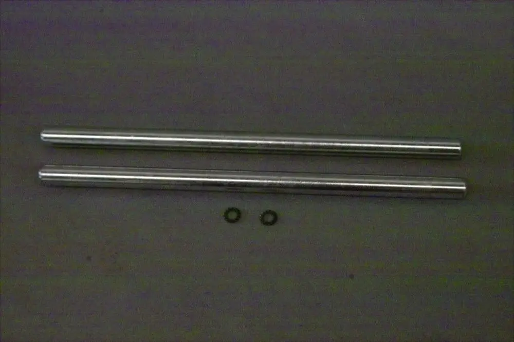 Zwei metallische Bolzen von Brötje, entlang einer grauen Unterlage angeordnet, mit zwei kleinen Ringen darunter.