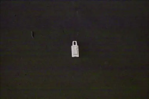 Weißer Kunststoffstecker mit Aussparungen, der möglicherweise für eine Brötje Bedieneinheit verwendet wird, auf dunkelgrauem Hintergrund.
