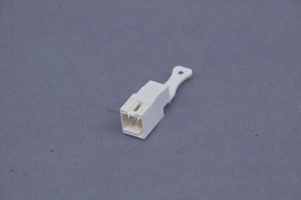 Weißer Stecker auf grauem Hintergrund, möglicherweise von Brötje, mit einfachem Design und zwei Kontaktöffnungen.