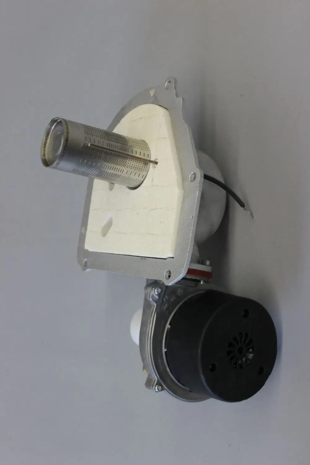 Brötje Brennereinheit mit zylindrischem Element und Motor. Die Komponente zeigt einen Metallring und eine Montageplatte aus hellem Material.