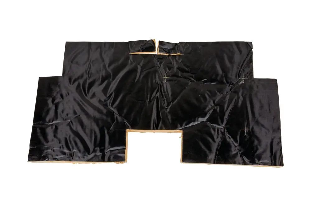 Schwarze Iso-Matte, die für die Isolierung eines Kesselblocks von Brötje geeignet ist. Die Matte zeigt Falten und hat Aussparungen für Befestigungen.